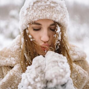 femme avec bonnet, écharpe, gants et manteau dans la neige